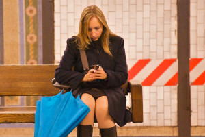 Mujer mirando su celular en la estación de metro
