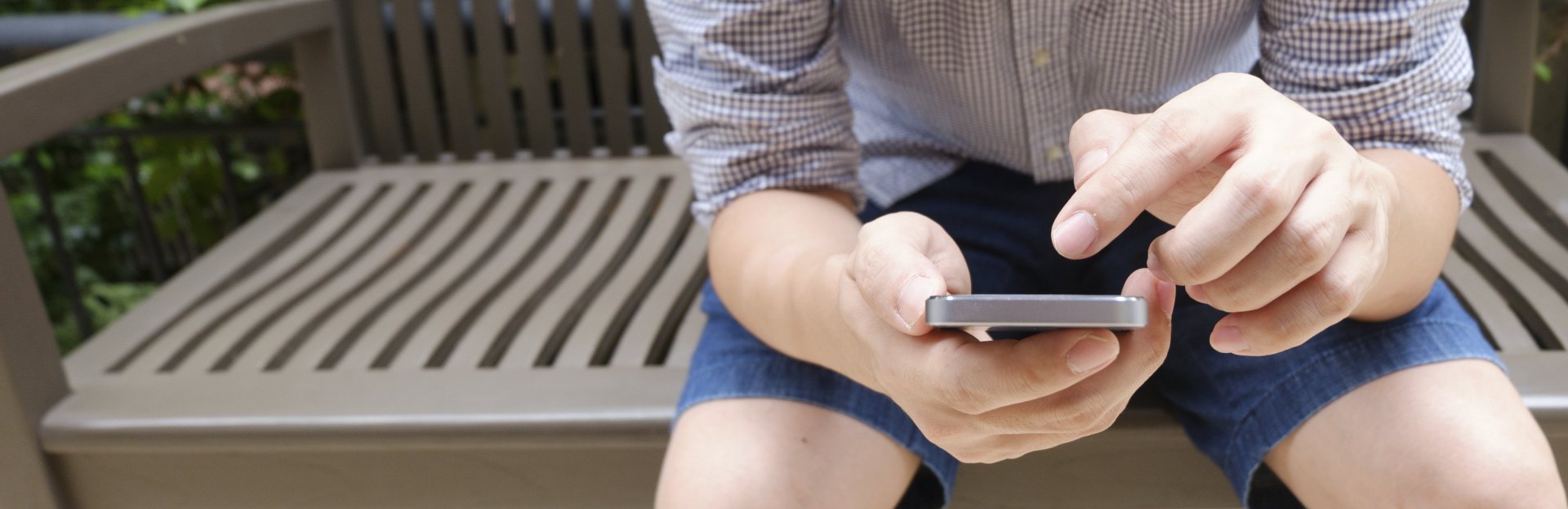 Joven sentado en una banca usando un smartphone