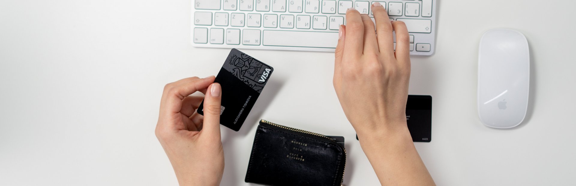 Manos sobre un teclado sosteniendo una tarjeta de crédito